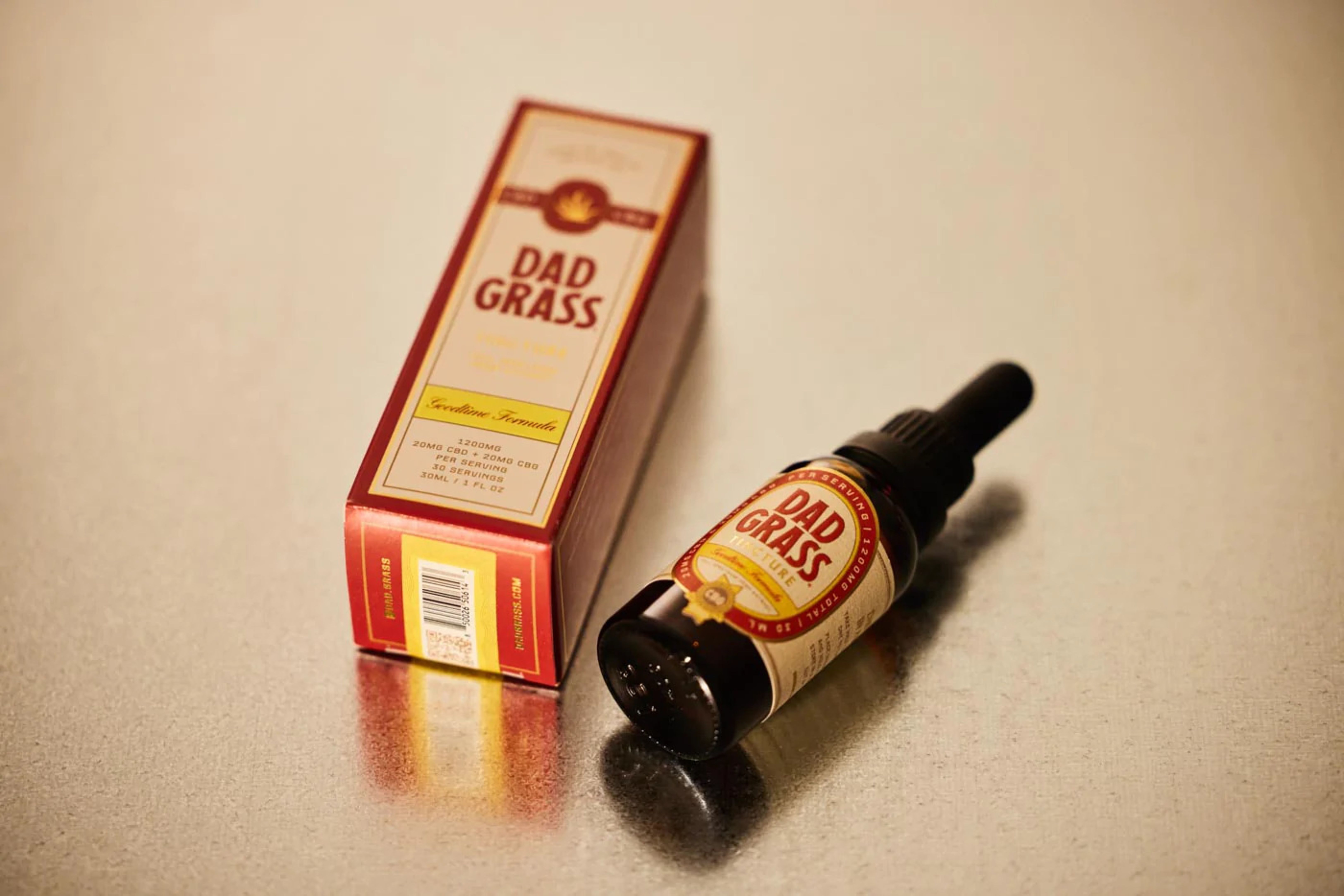 Still life of a branded cannabis tincture bottle and outer packaging on a reflective surface