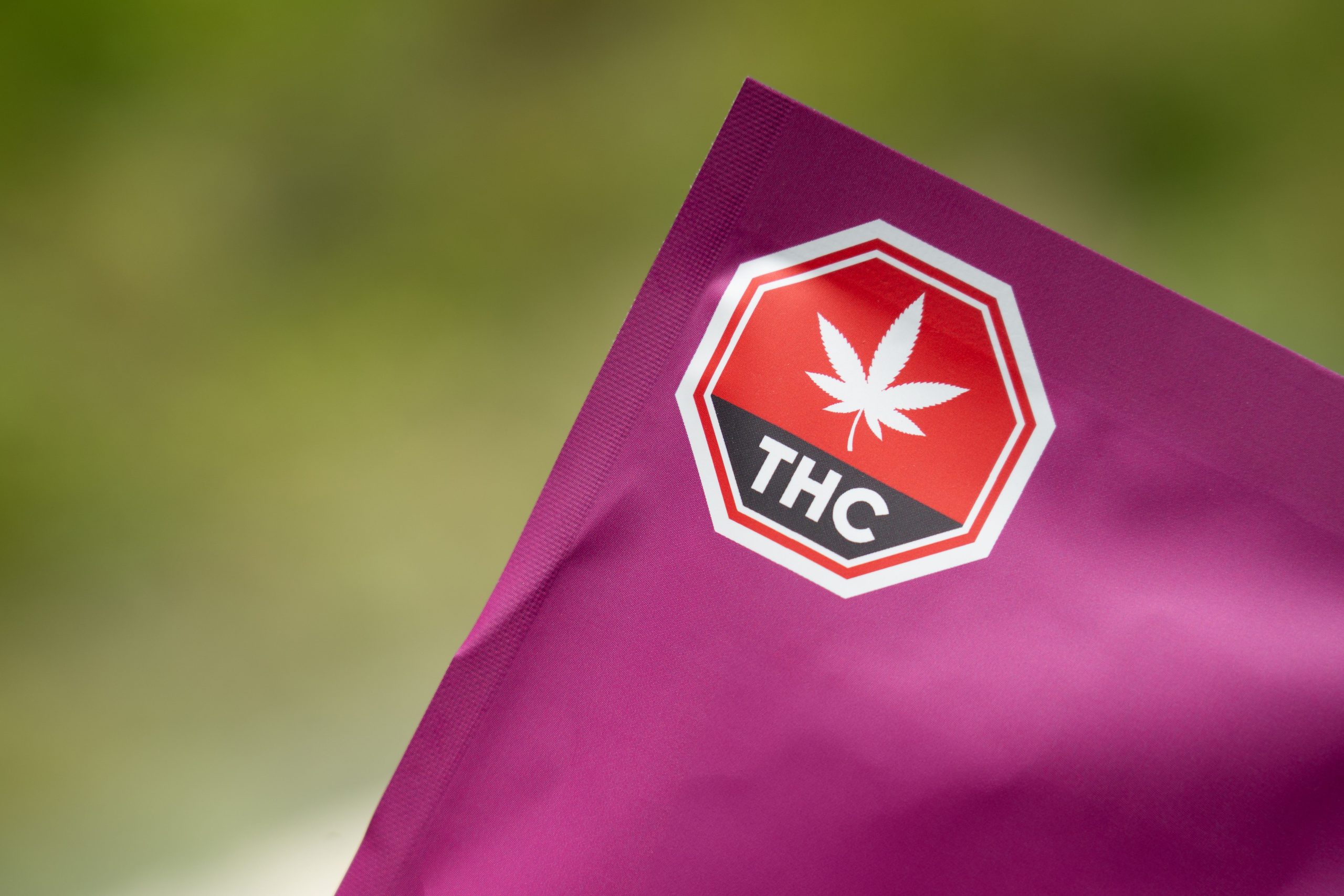 Cannabis packaging with a THC warning label on a purple background showing regulatory compliance
