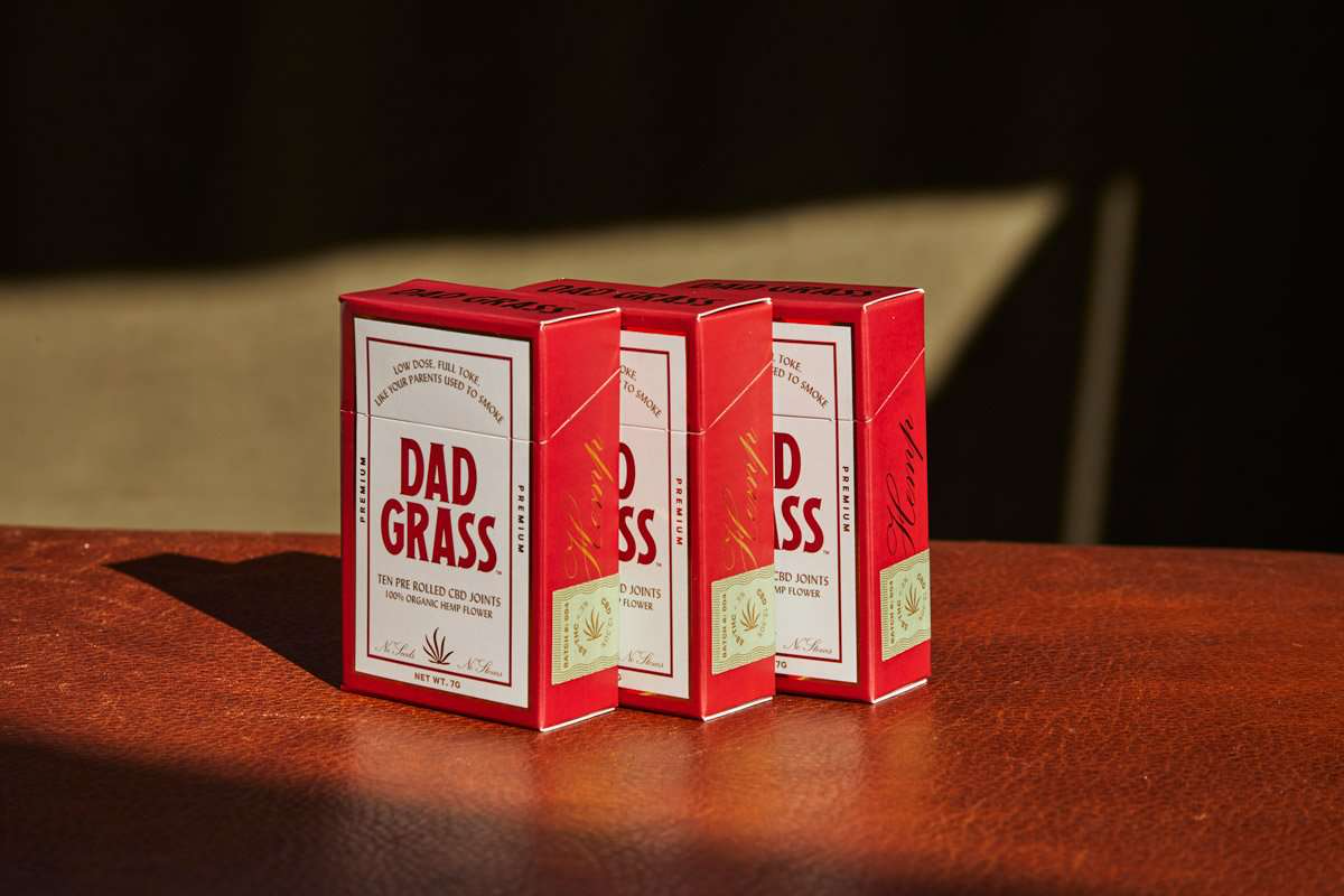Red custom CBD joint boxes on a leather surface highlighting branded pre-roll packaging