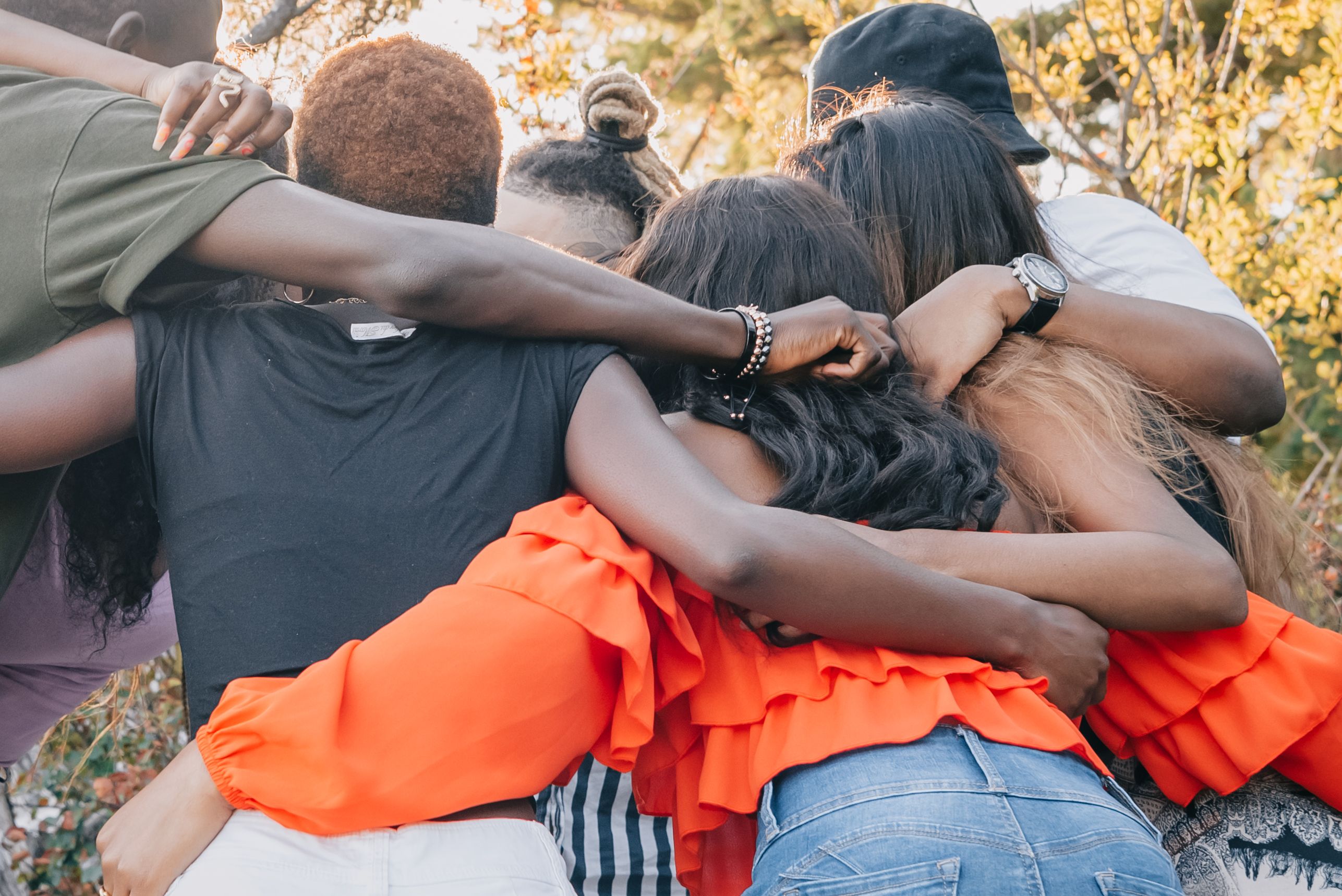 A diverse group of friends sharing a warm embrace outdoors, symbolizing the joy of feeling wanted and belonging