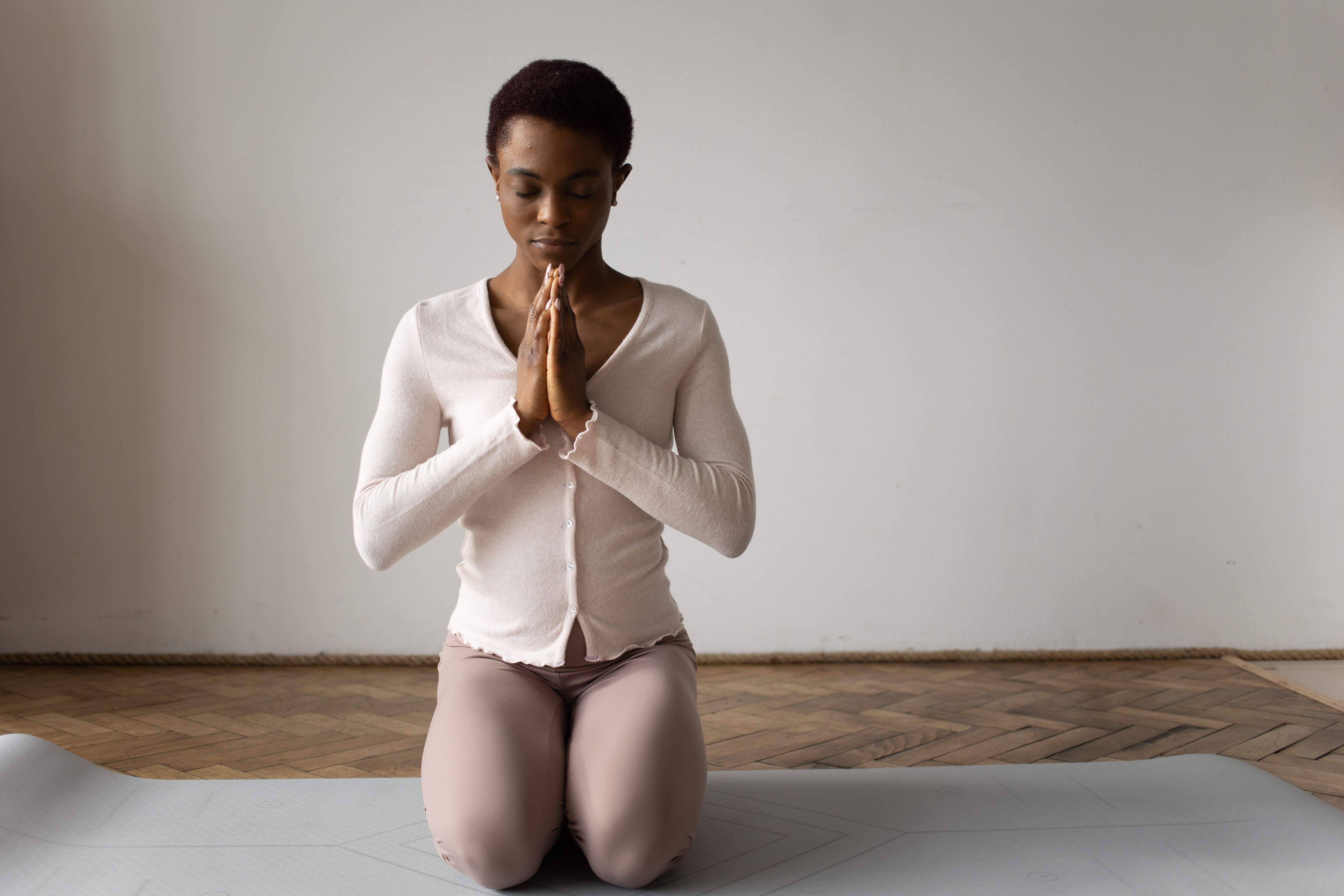A woman meditating serenely on a yoga mat indoors, cultivating inner peace and self-compassion