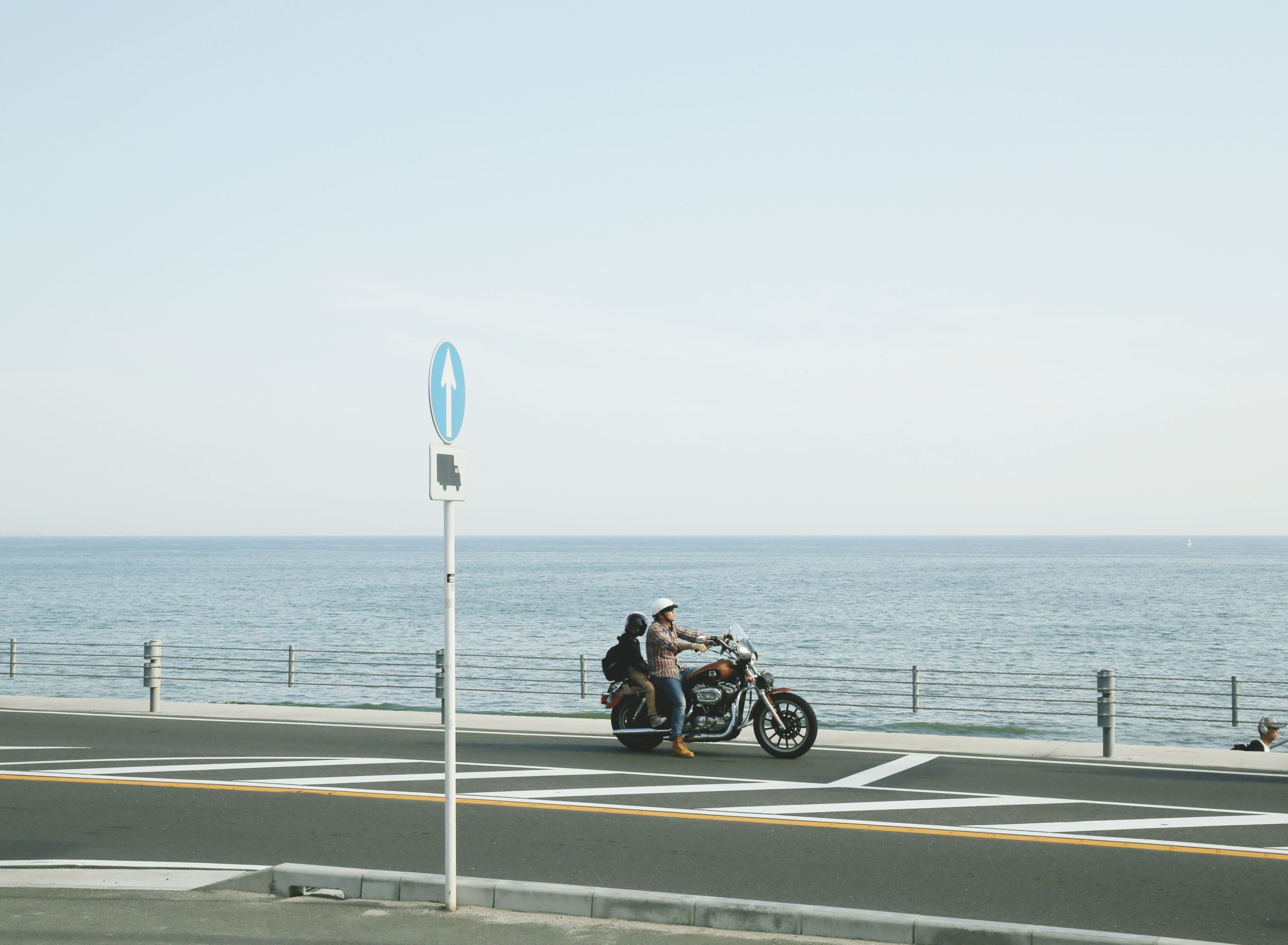 Motorcycle rider cruising along a scenic coastal road with an open ocean view on a summer day