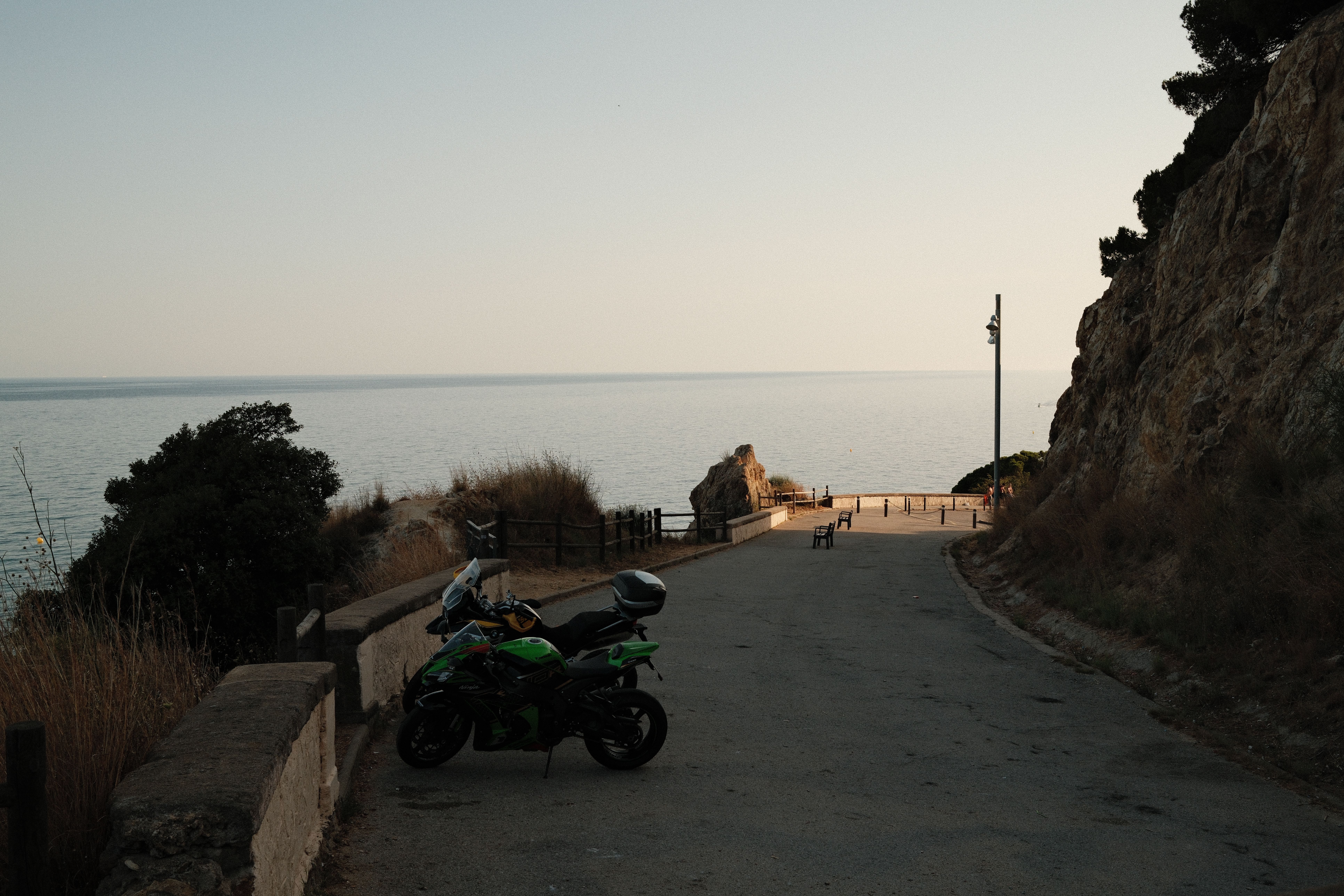 Parked motorcycle on a serene coastal road at dusk with a sea view