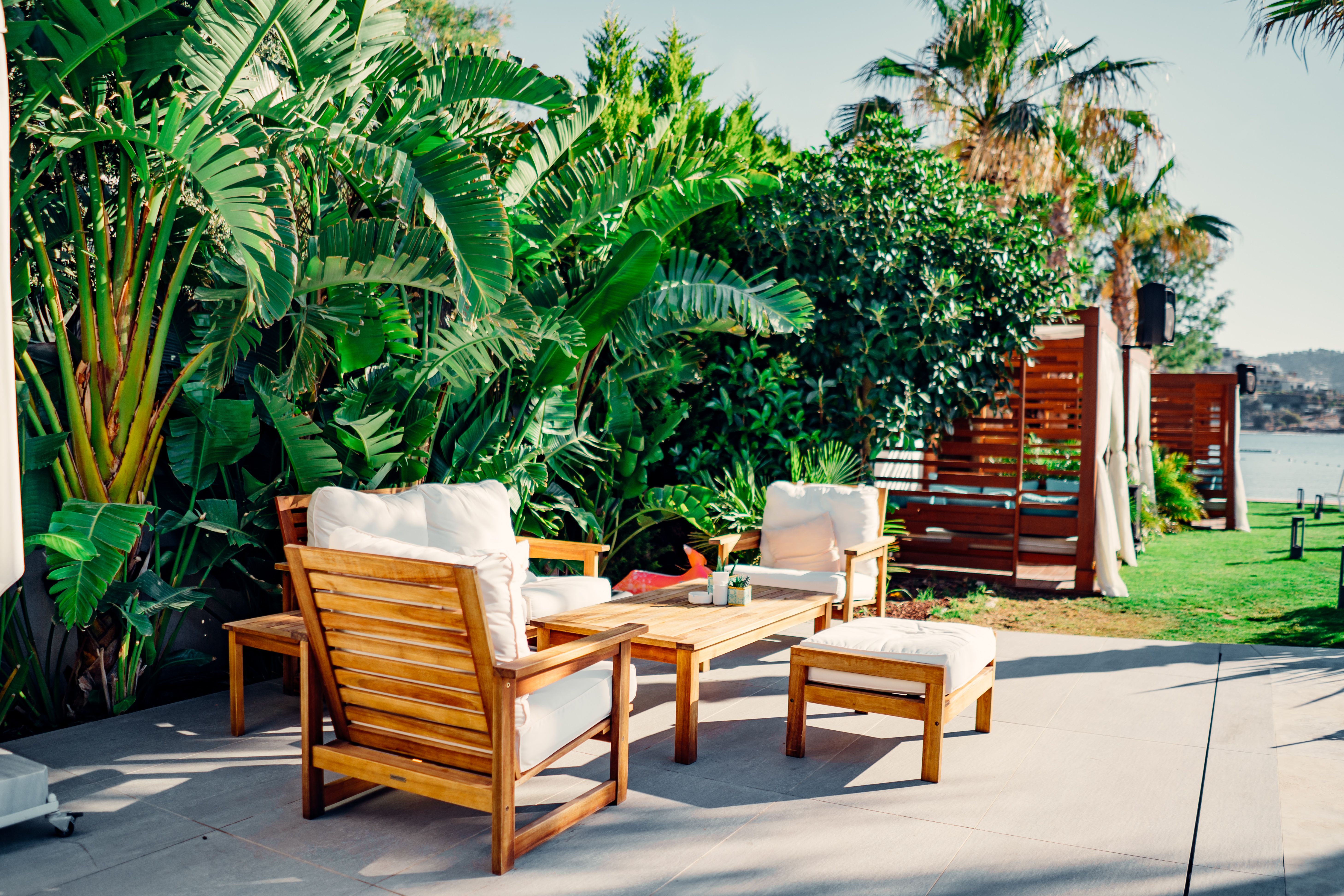 Outdoor patio with weather-resistant wooden furniture and tropical greenery